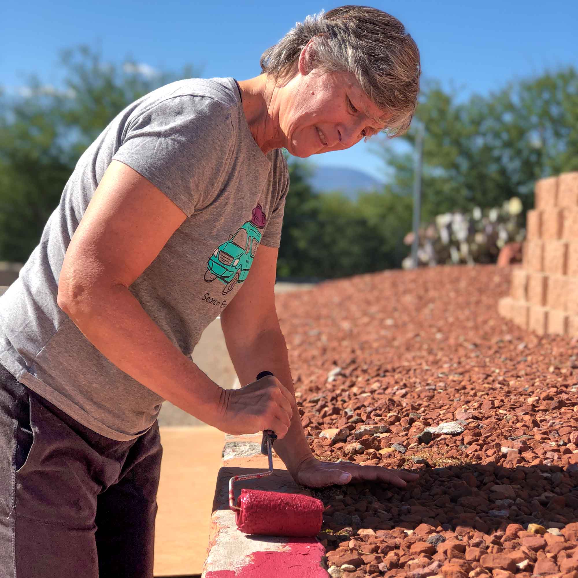 A volunteer for Rainbow Acres helping to paint the curb red again